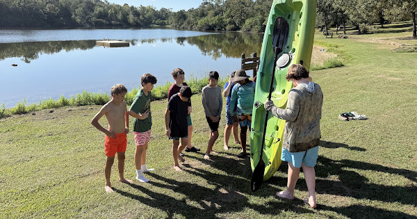 Scouts preparing a kayak beside the lake at Fort Boggy